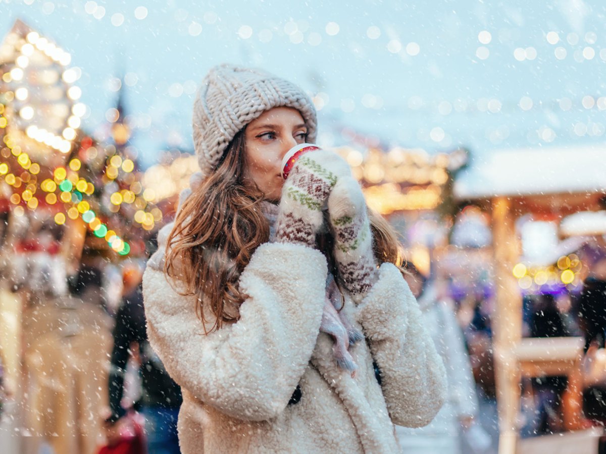 Eine Frau mit einem Glühwein auf dem Weihnachtsmarkt.