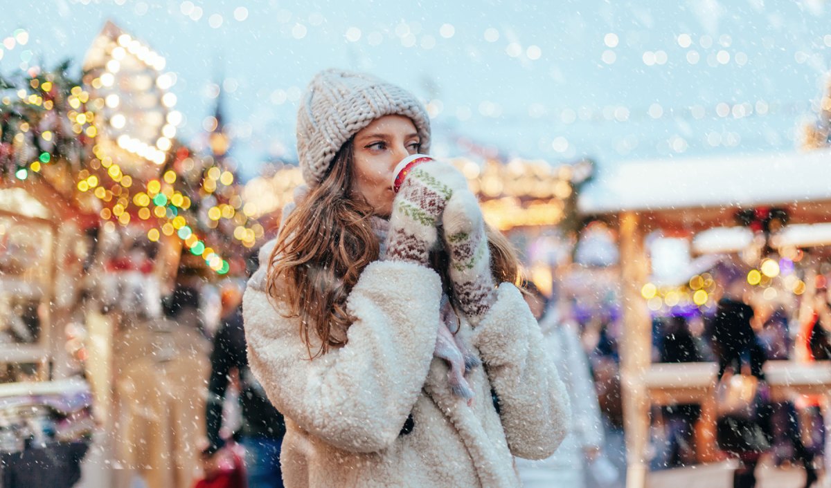 Eine Frau mit einem Glühwein auf dem Weihnachtsmarkt.