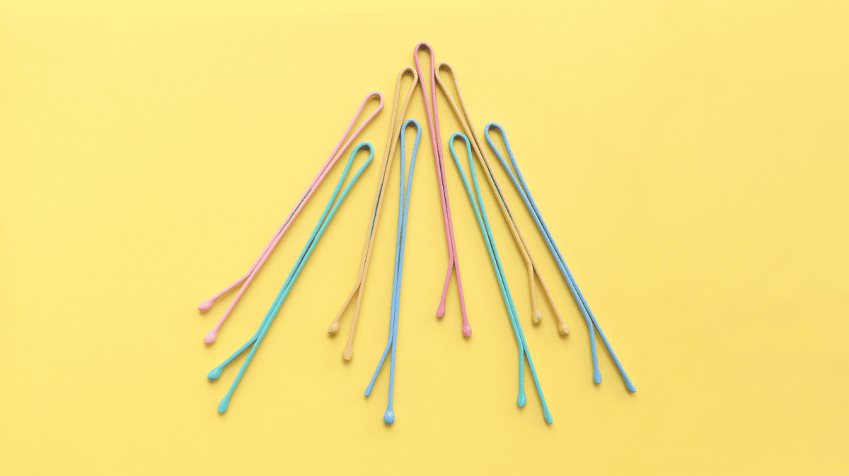 Draufsicht auf bunte pastellfarbene Haarspangen auf gelbem Hintergrund.