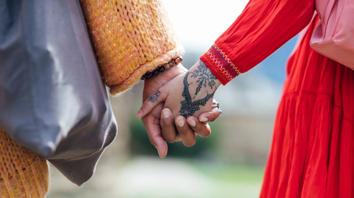 Zwei Personen halten Händchen, eine davon hat ein Boho Tattoo auf dem Handrücken