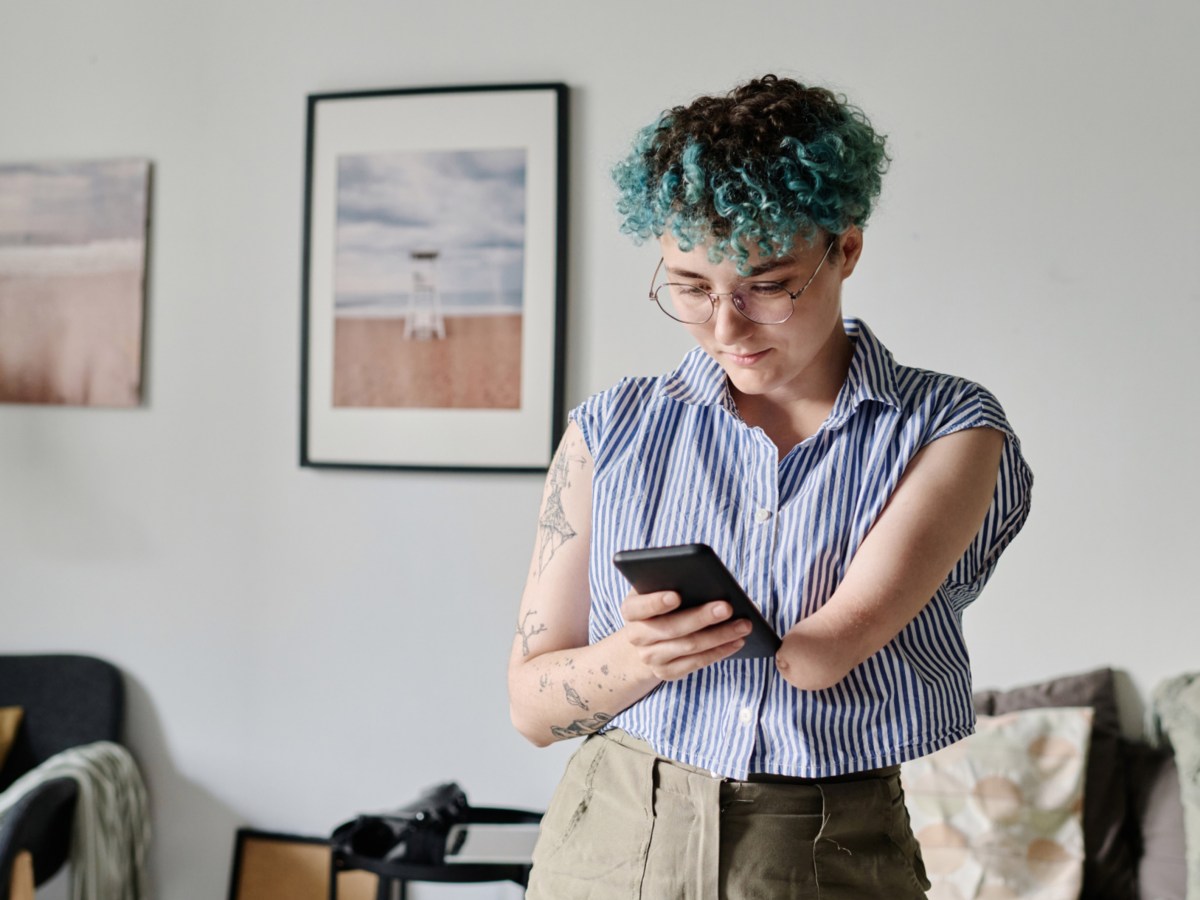 Frau mit Handy in der Hand, die auf den Bildschirm schaut