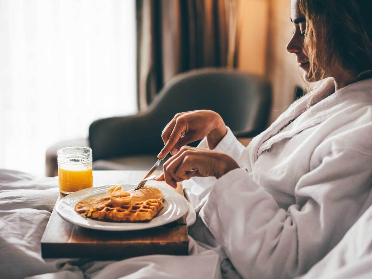Frau beim Fr&uuml;hst&uuml;ck im Hotelzimmer. Waffeln zum Fr&uuml;hst&uuml;ck