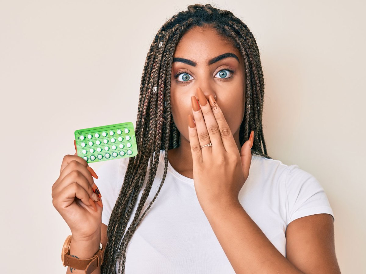 Junge Frau h&auml;lt einen Antibabypille-Blister in der Hand und schaut erschrocken.