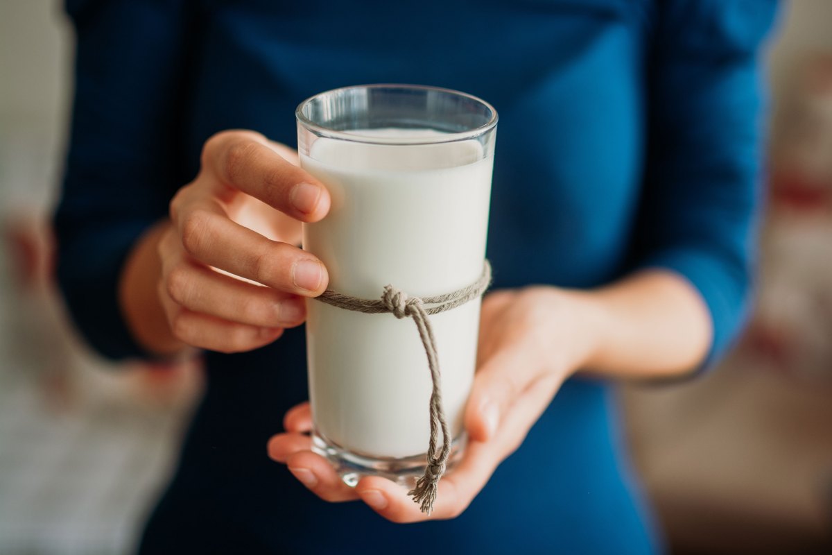 Junge Frau hält ein Glas Milch in der Hand.