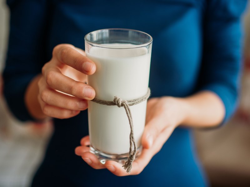 Junge Frau hält ein Glas Milch in der Hand.