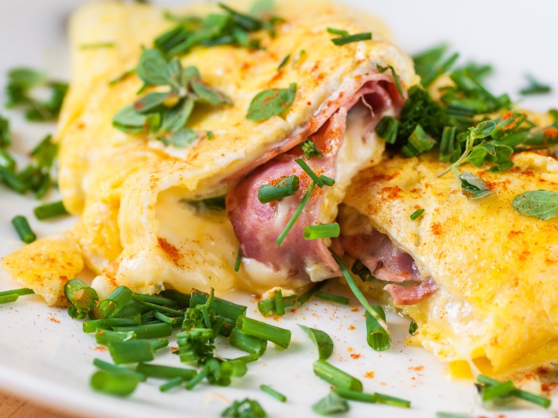 Low Carb Frühstück mit Omelette mit Käse und Schinken darauf Kräuter