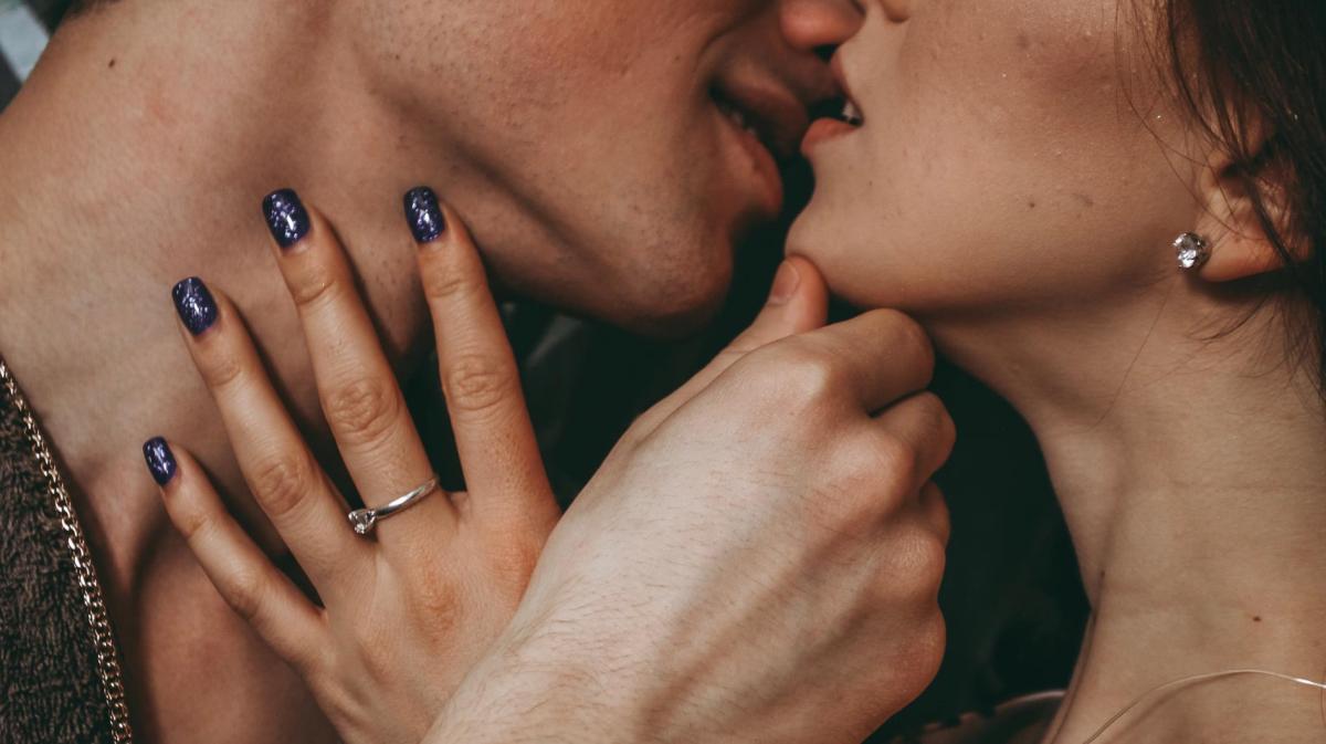 Nahaufnahme: Mann küsst Frau leidenschaftlich. Sie streicht mit ihrer Hand über seinen Hals.