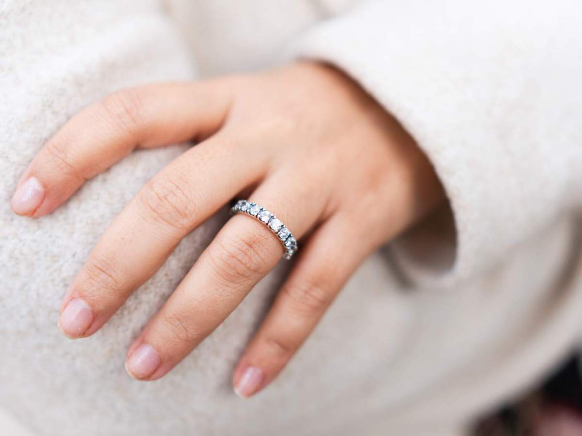 Frau mit weißem Pullover und verschränkten Armen trägt einen mit Steinen besetzten Ring.