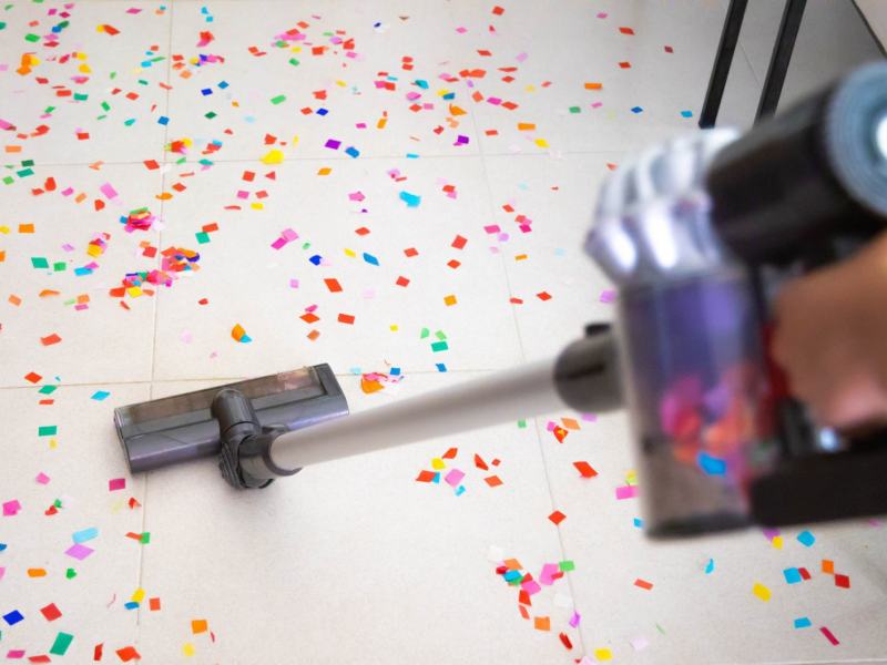 Person saugt mit einem Staubsauger Konfetti auf.