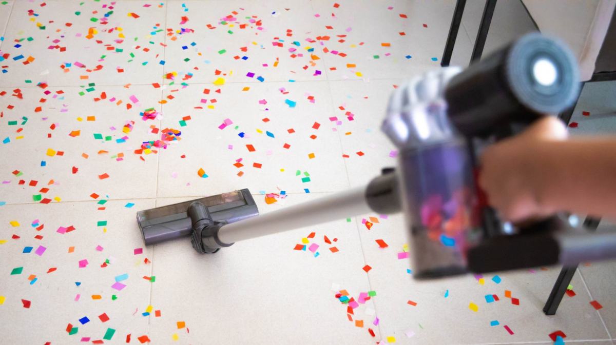 Person saugt mit einem Staubsauger Konfetti auf.