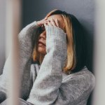Frau sitze traurig auf dem Boden, die Hände vor dem Gesicht