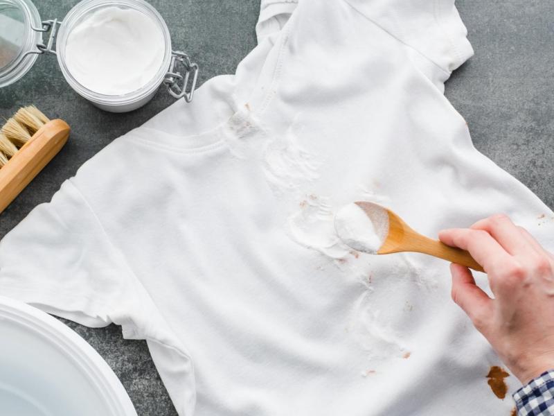 Person reinigt ein weißes T-Shirt mit Hausmitteln.