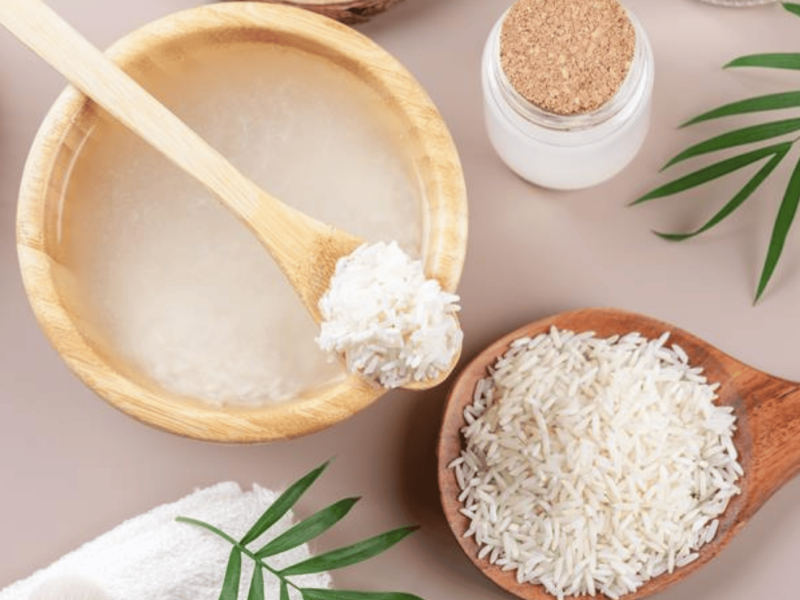 Hausgemachtes kosmetisches Reiswasser mit Zutaten und Beauty-Set auf beigefarbenem Hintergrund