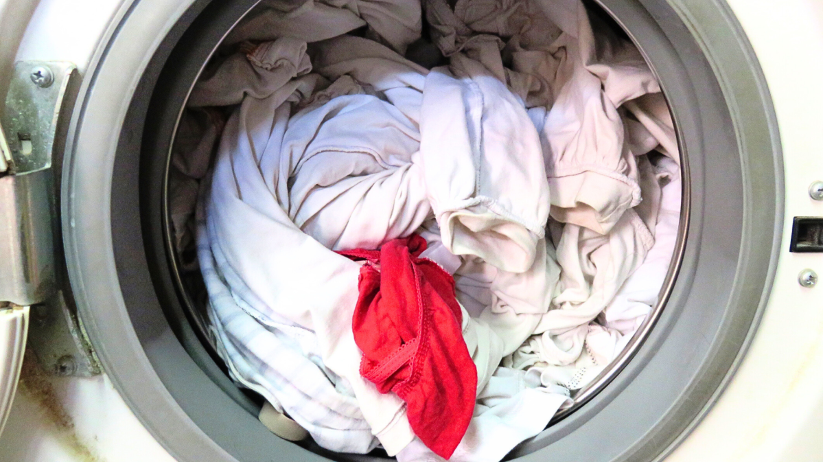 Rotes Textilstück in einer Trommel mit weißer Wäsche.