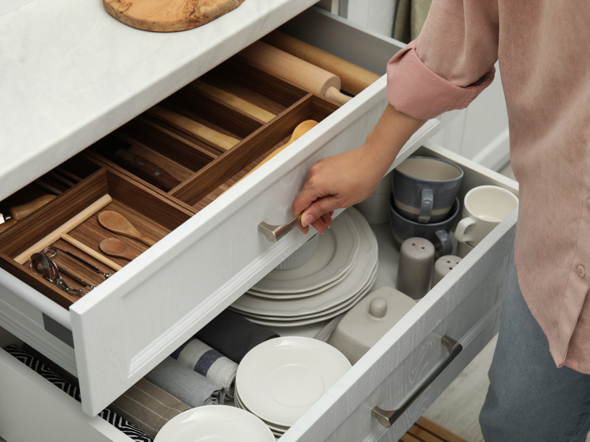 Eine Frau öffnet eine Schublade um Ordnung in der Küche zu schaffen