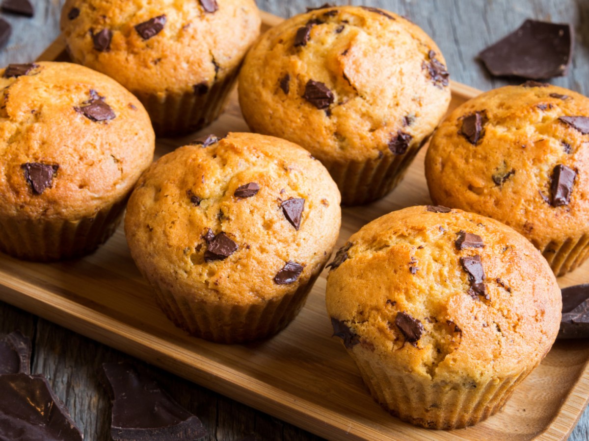 Muffins mit Schokostückchen auf einem Holzbrett.