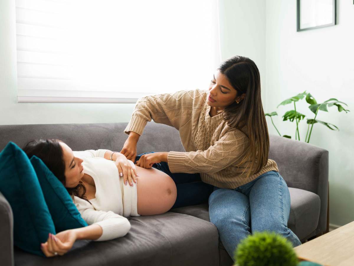 Hebamme untersucht den Bauch einer Schwangeren in ihrem zu Hause.