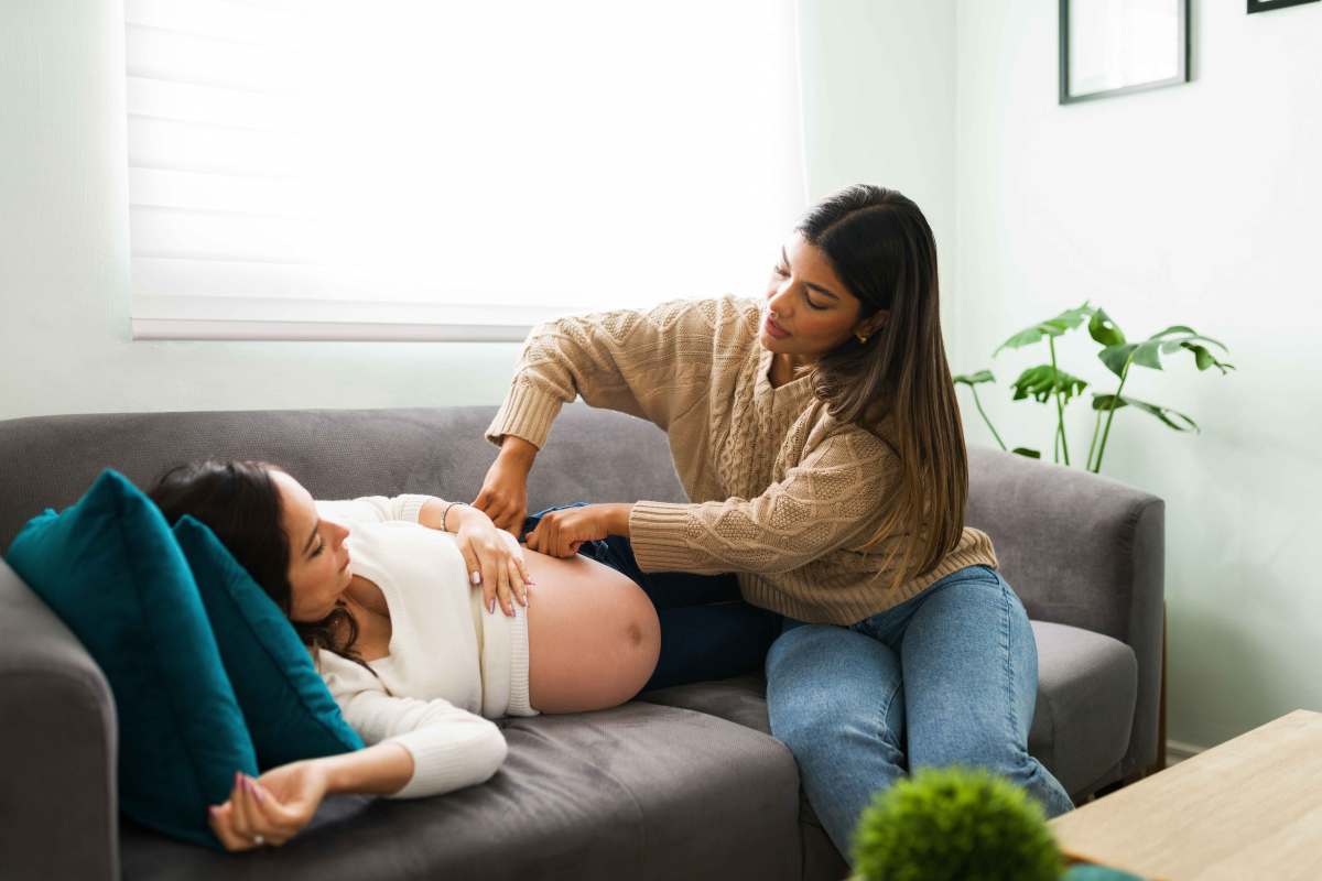 Hebamme untersucht den Bauch einer Schwangeren in ihrem zu Hause.