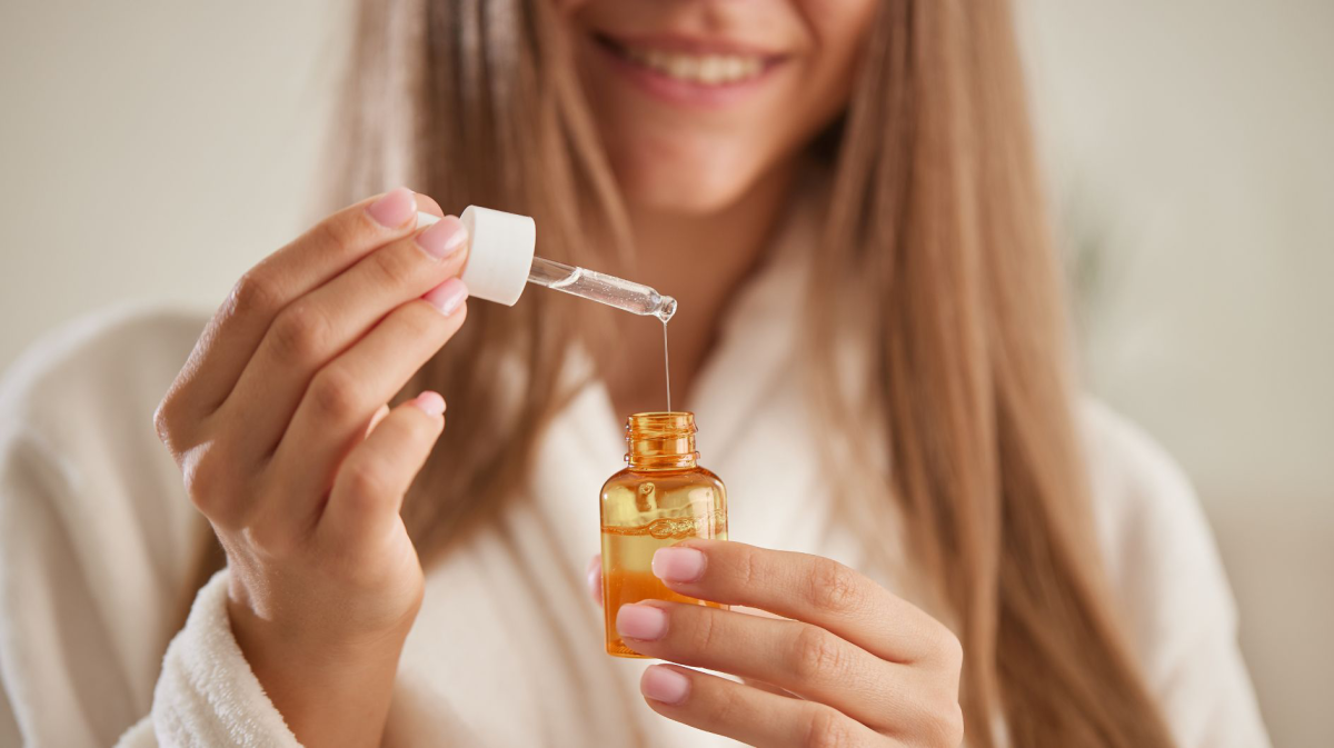 Frau mit langem Haar hält Serum in den Händen