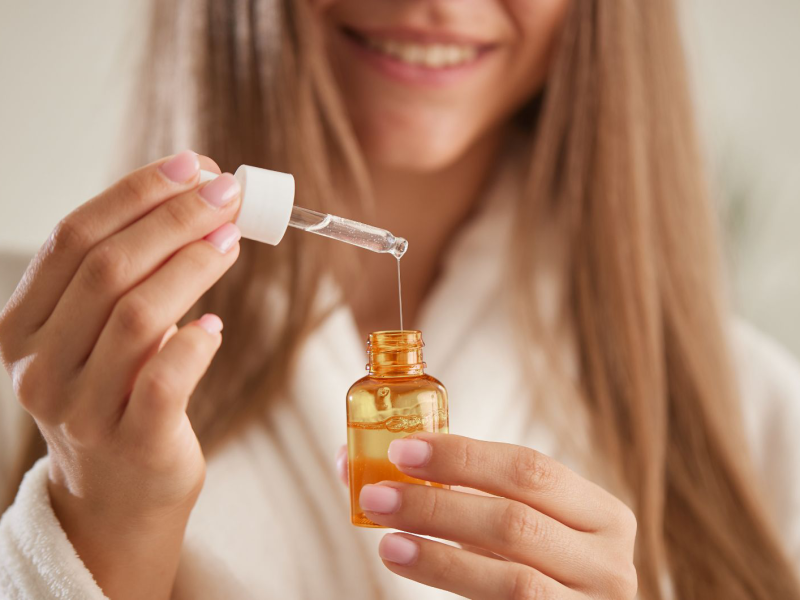 Frau mit langem Haar hält Serum in den Händen