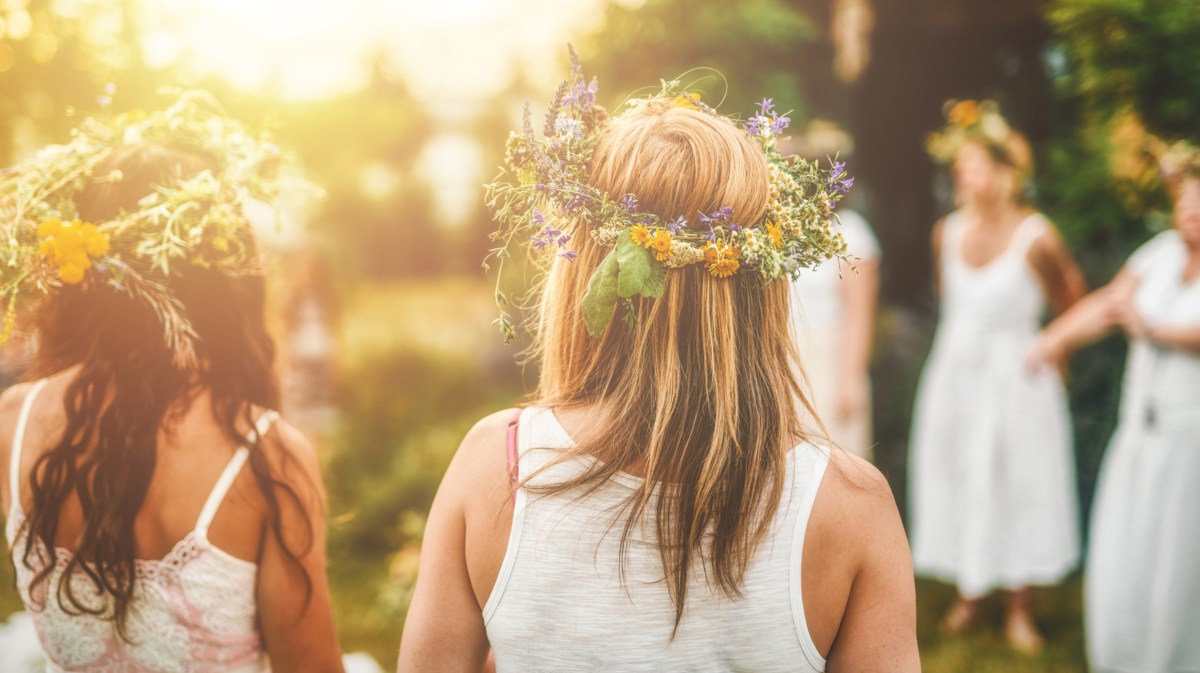 Mädchen feiern Mittsommer und tragen Blumenkränze.