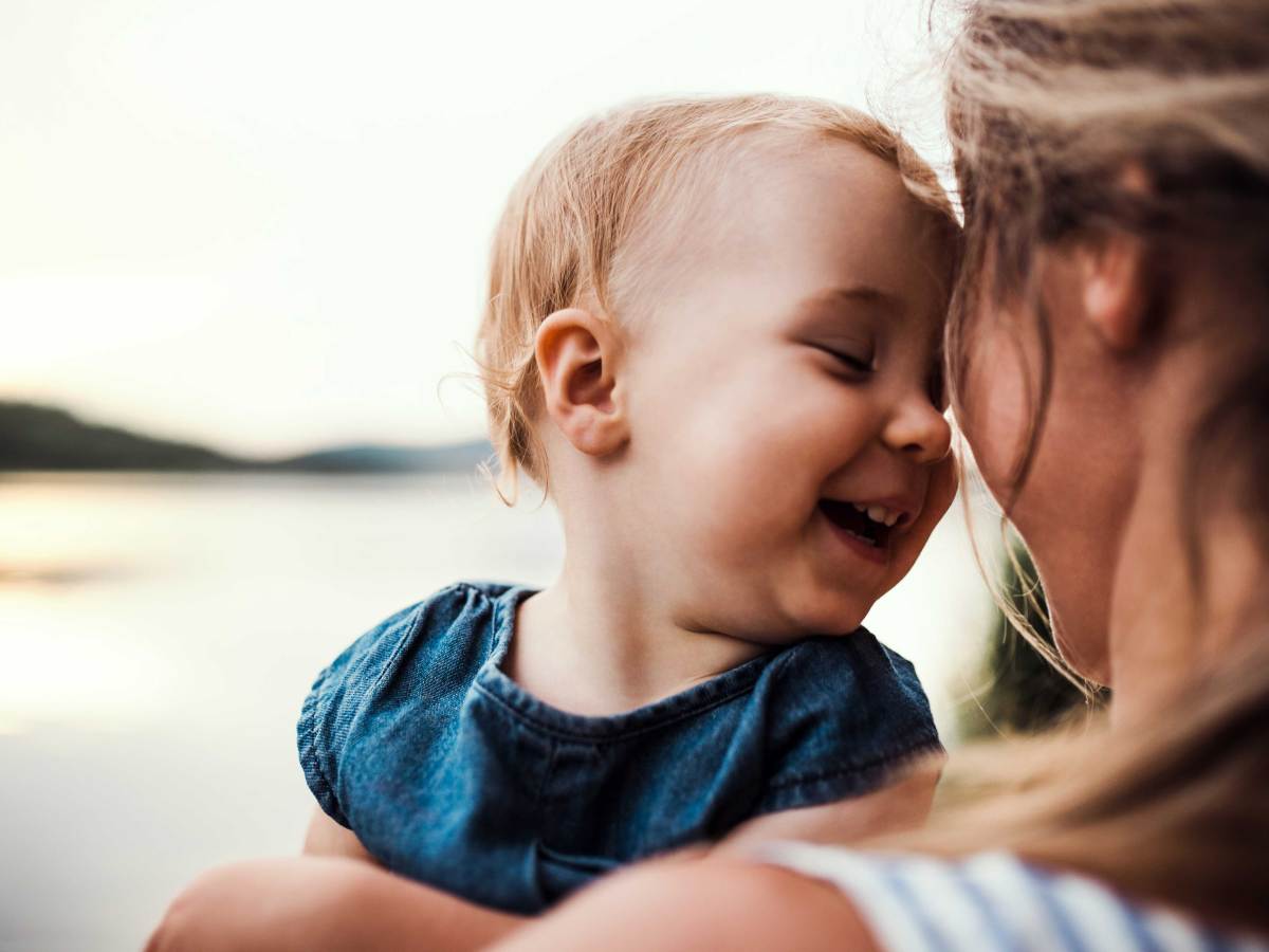 Kleines Kind lehnt seinen Kopf glücklich gegen den seiner Mutter.