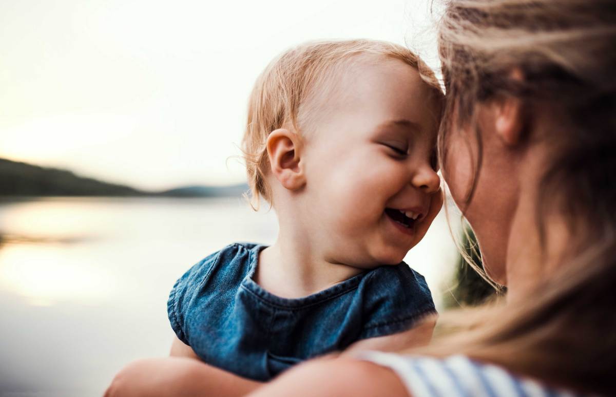 Kleines Kind lehnt seinen Kopf glücklich gegen den seiner Mutter.