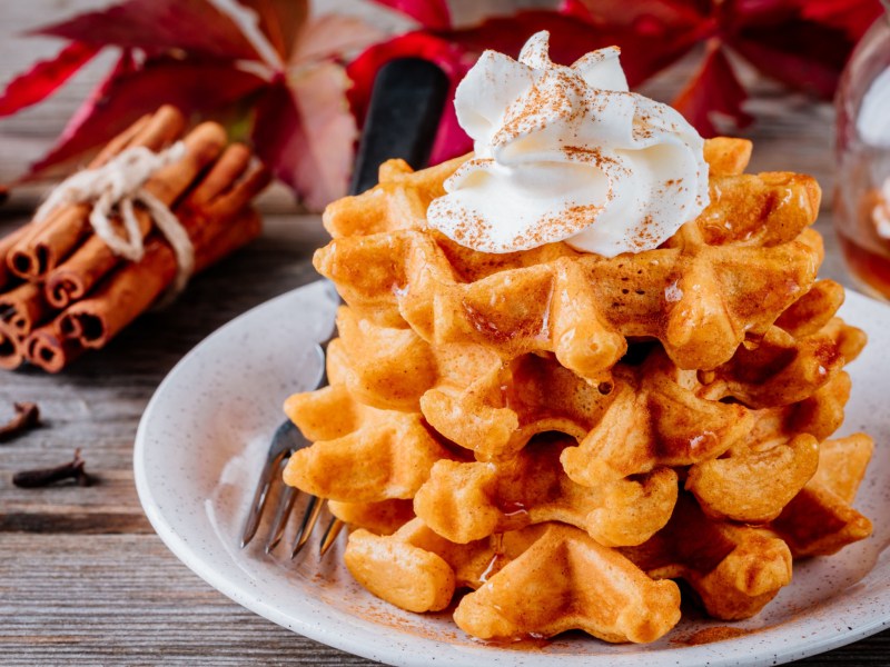 Kürbis-Waffeln mit Sahne auf weißem Teller.