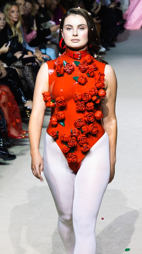 Junge Frau mit roten Ohrringen präsentiert einen roten Latex-Body mit kunstvollen Lego Botanicals-Rosen.