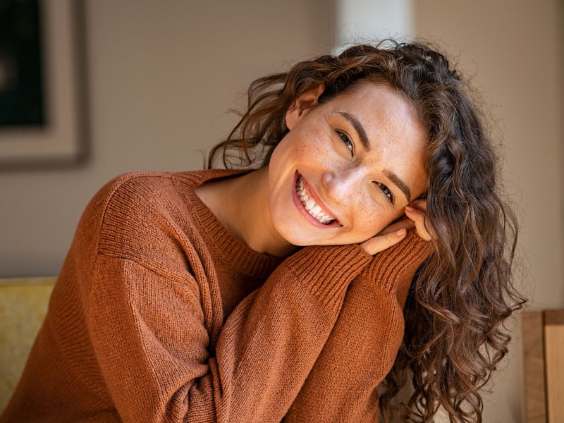 Junge Frau mit Locken lächelt in die Kamera.