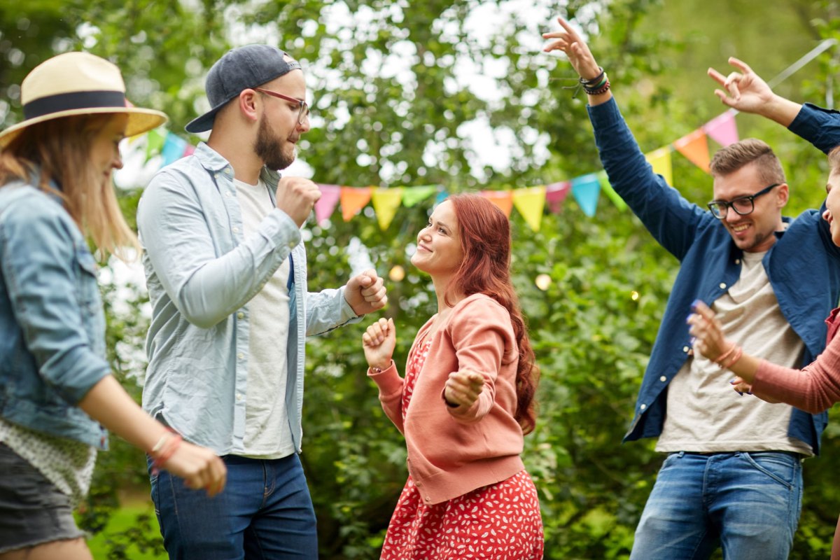 Freunde, die zusammen im Garten feiern und tanzen