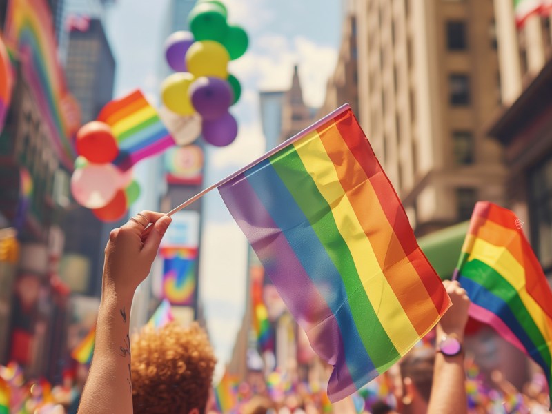 CSD Stra&szlig;enfest mit Regenbogenflaggen durch eine Stadt.