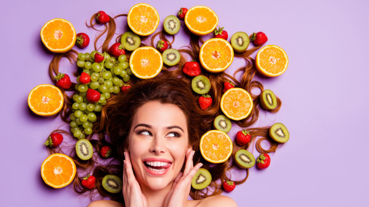 Frau, deren Haare von Früchten umgeben sind