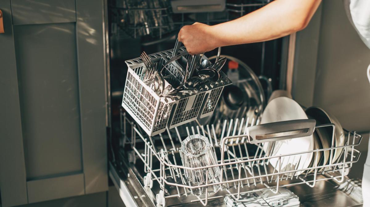 Frau räumt Spülmaschine aus.