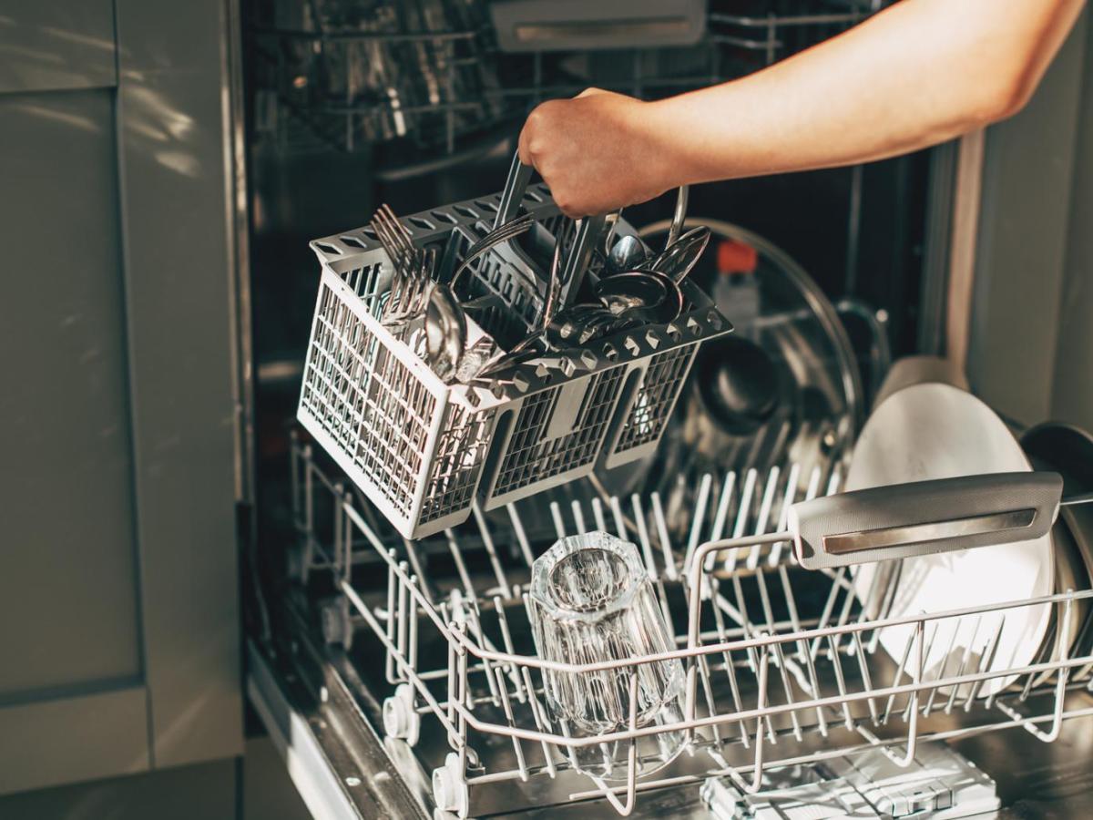 Frau räumt Spülmaschine aus.