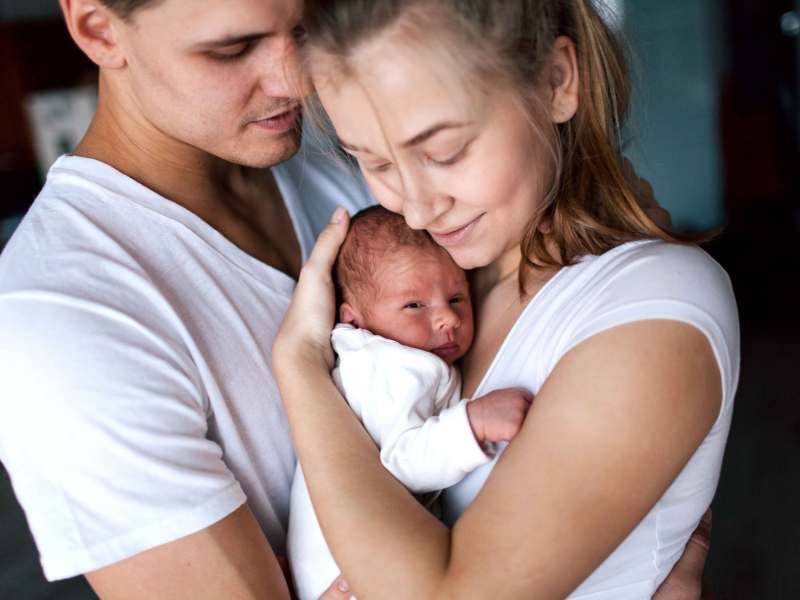 Junges Paar hält sein Neugeborenes in den Armen.