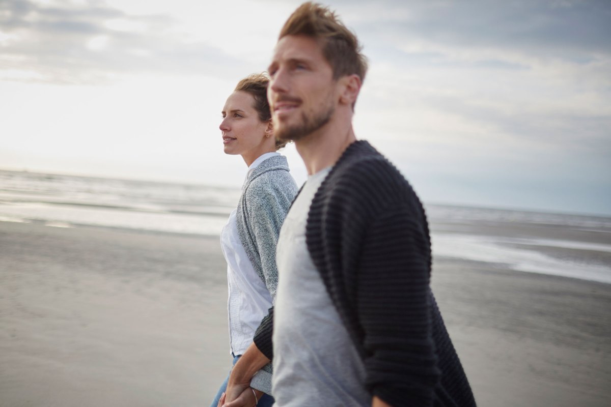 Ein Paar läuft Hand in Hand über den Strand.