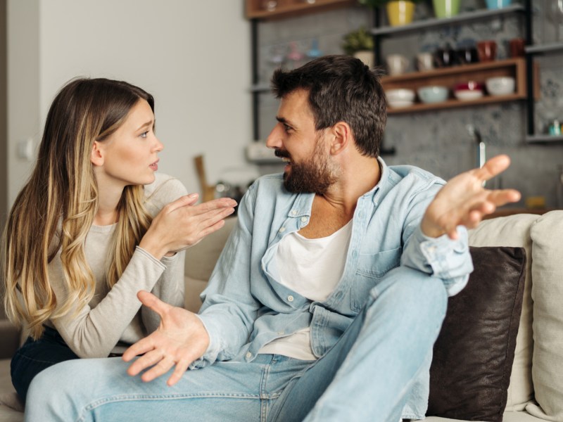 Mann und Frau auf dem Sofa, die mit den Händen gestikulieren und sich streiten