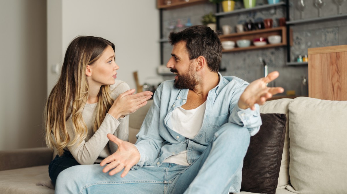 Mann und Frau auf dem Sofa, die mit den Händen gestikulieren und sich streiten