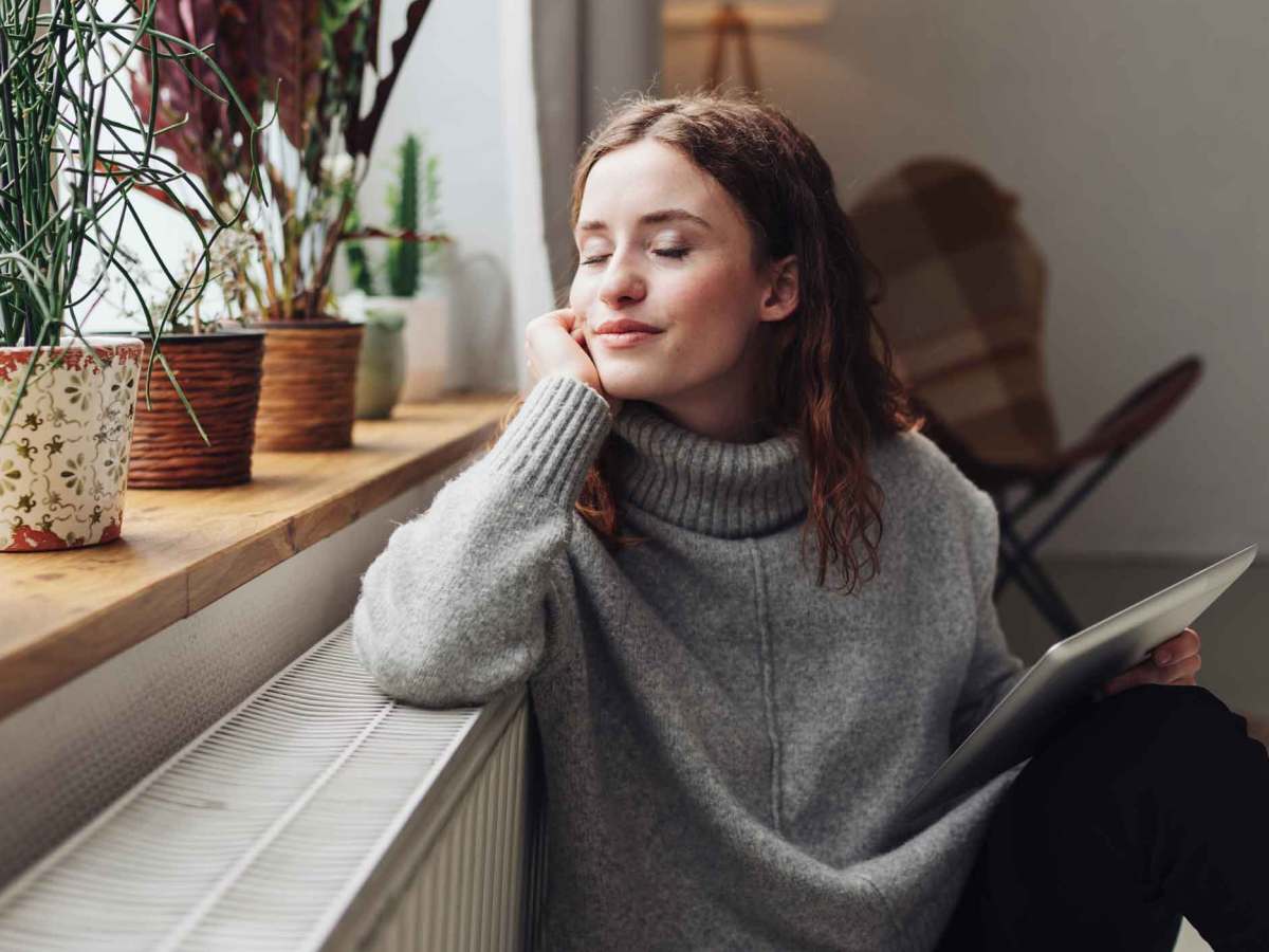 Frau sitzt an der Heizung.