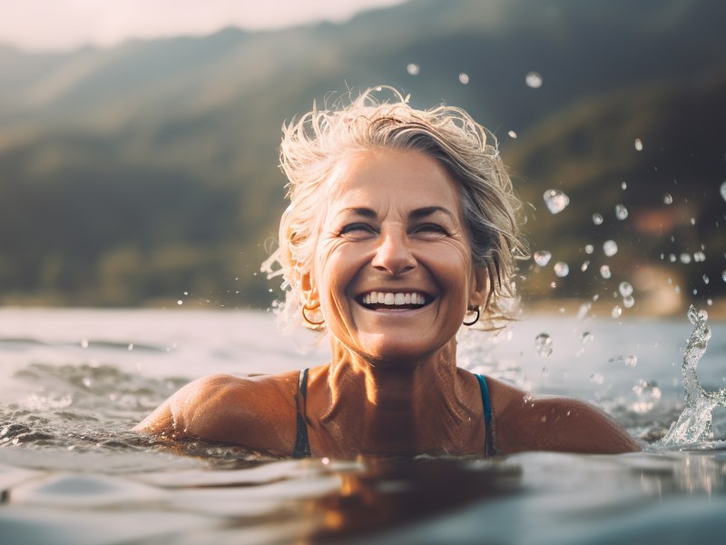 Ältere Frau schwimmt im See und genießt ihre Rente.