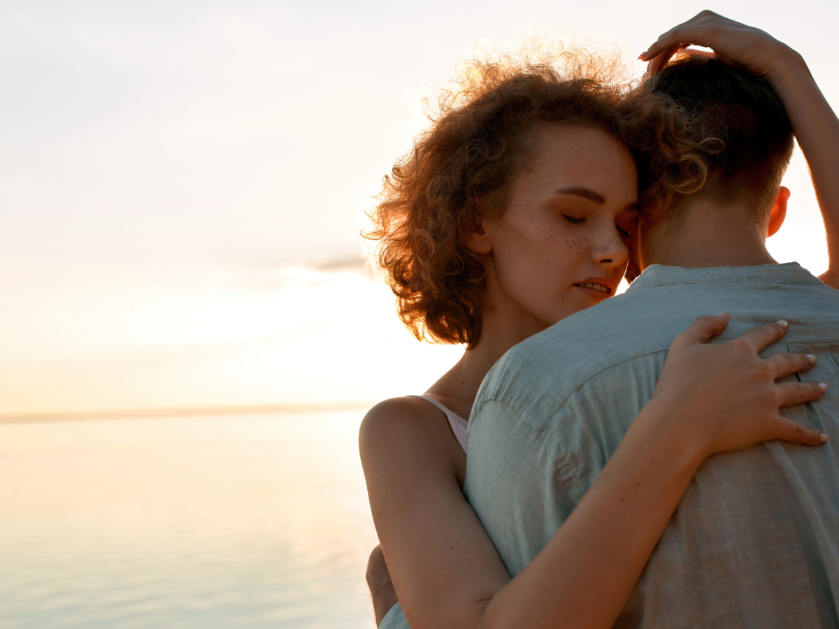 P&auml;rchen am Wasser beim Sonnenuntergang, das sich liebevoll umarmt.