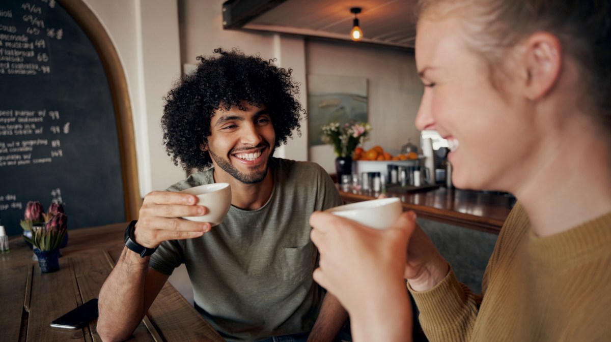 Mann und Frau beim Kaffeetrinken, die sich gegenseitig anlächeln