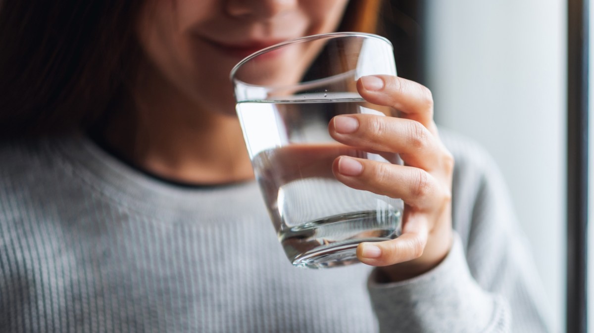 Frau trinkt aus Wasserglas.