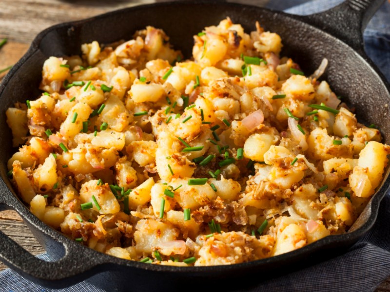 Bratkartoffeln mit Petersilie und schwarzer Pfanne.