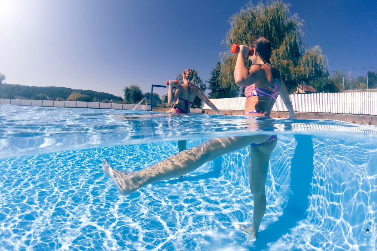 zwei Frauen trainieren Aquagymnastik im Pool