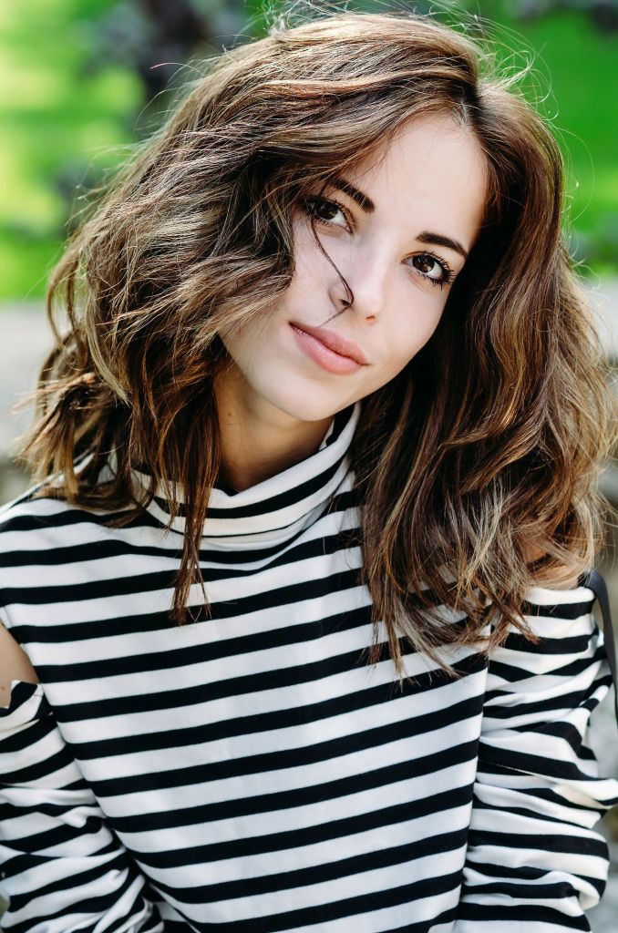 Frau in gestreiftem Pullover mit lockigem, dicken Haaren