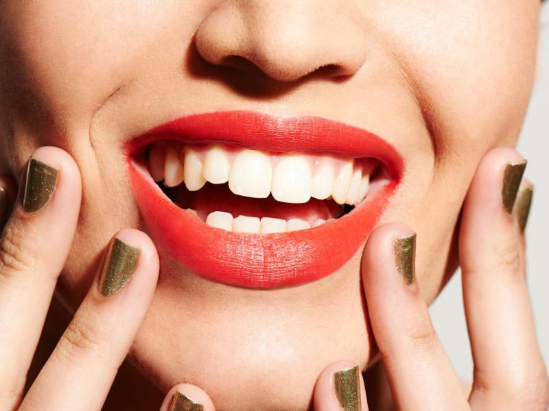 Frau mit Lippenstift lacht und hat ein strahlendes weißes Lächeln.