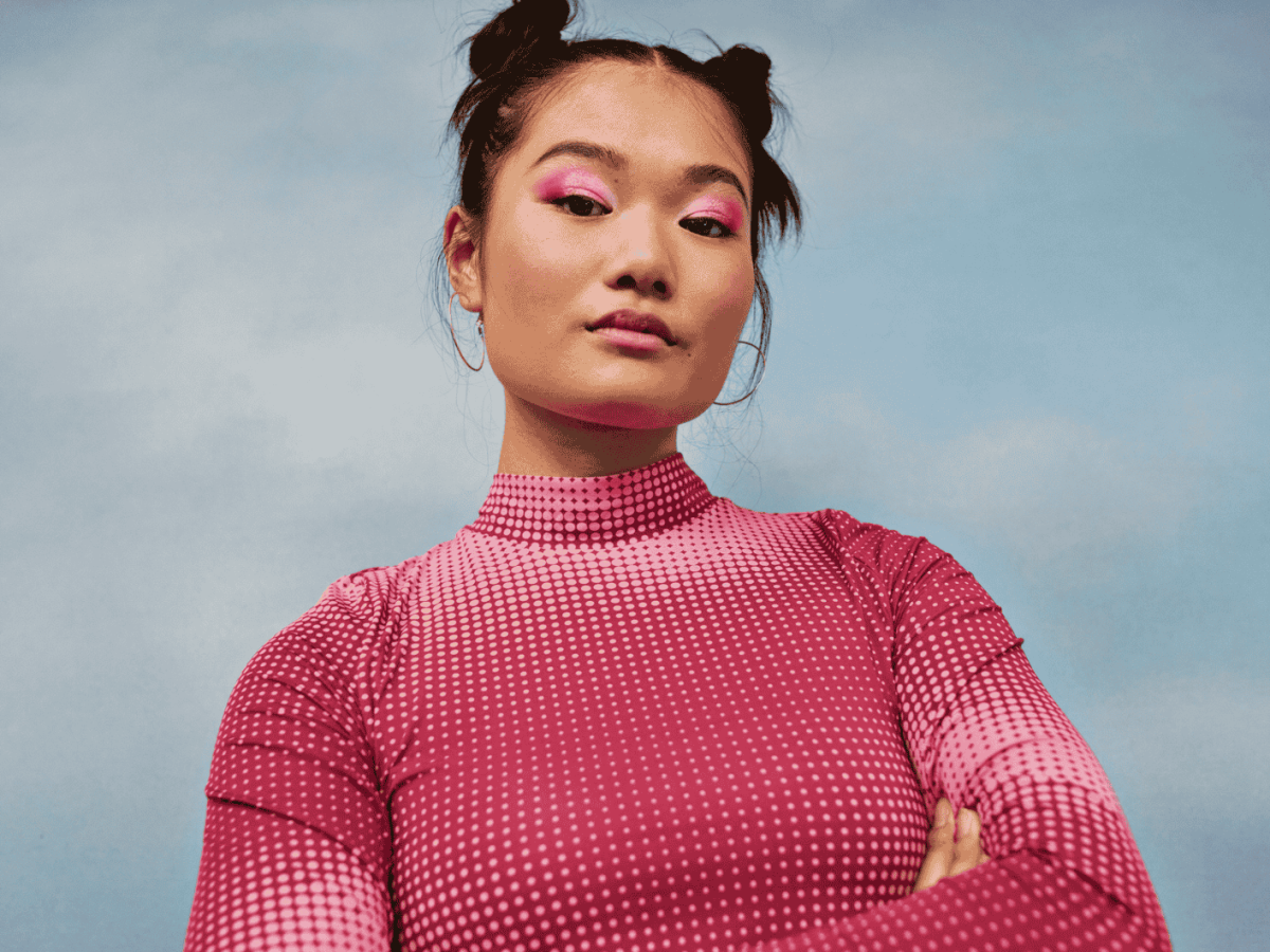 Frau mit pinkem Pullover schaut selbstbewusst in die Kamera