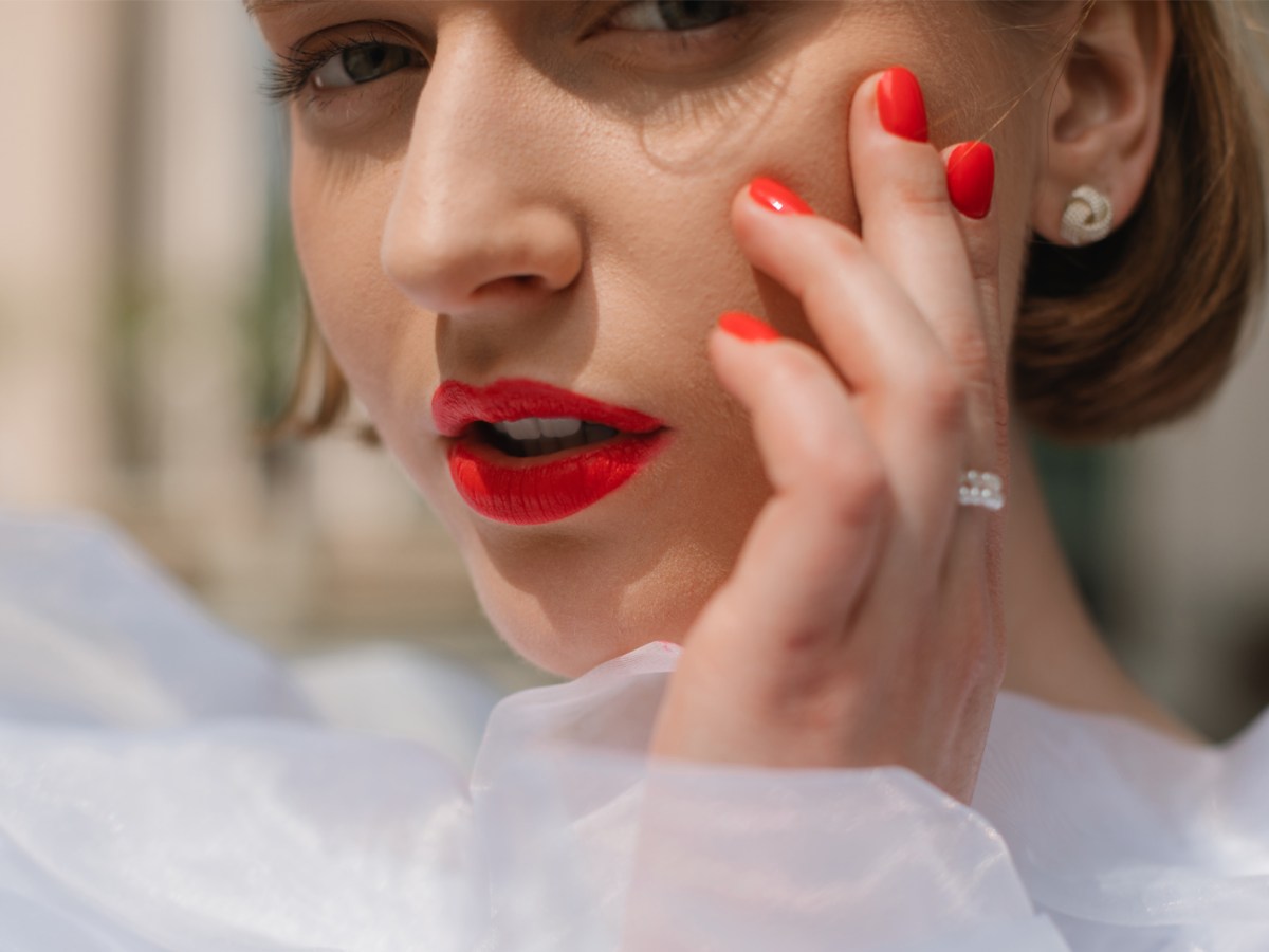 Frau mit roten Lippen und roten Nägeln.